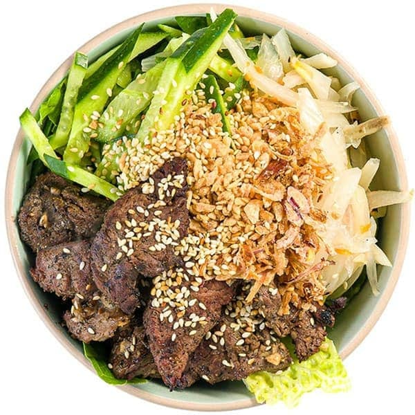 Overhead view of a Vietnamese bowl with grilled beef, cucumbers, pickled vegetables, and crispy fried onions.