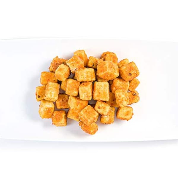 A pile of golden-brown fried tofu cubes, seasoned and ready to eat, on a white rectangular plate.