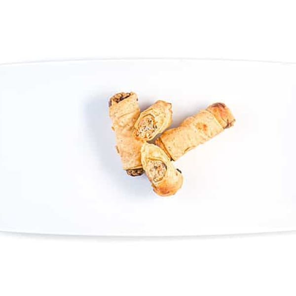 Three crispy Vietnamese imperial rolls, two whole and one cut open, on a white plate.
