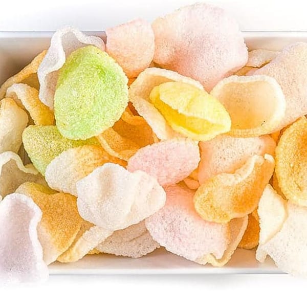 A close-up of colorful, crispy Vietnamese shrimp chips (Banh Phong Tom) in a white bowl.